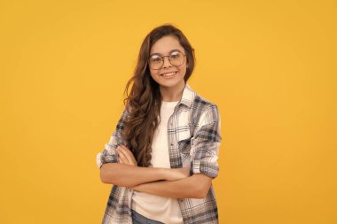 Sarı arka planda damalı gömlek ve gözlüklü mutlu genç çocuk..