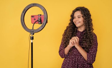 glad child with long curly hair making video for blog.