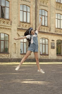 Sırt çantalı mutlu bir kız dışarı atlıyor..