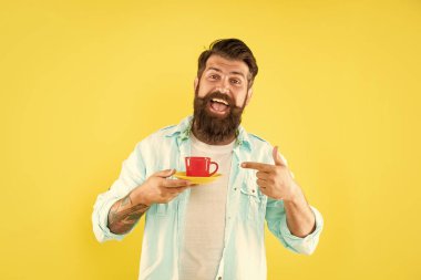 Tişörtlü, traşsız mutlu adam işaret parmağı sarı fonda kahve, kahve.
