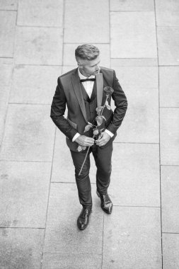 Nişan tarihi. Yakışıklı smokinli adam nişanı kutluyor. Nişan için gül hediyeli bir adam.