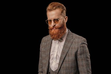 man in tuxedo menswear and glasses on background. photo of man in tuxedo menswear with beard. man in tuxedo menswear isolated on black. man in tuxedo menswear at studio.