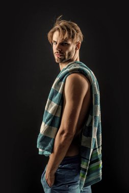 Stüdyo arka planında kaslı kaslı bir adam. Kaslı adam karın kaslarına havlu takıyor. Kaslı bir adamın fotoğrafı. Siyah arka planda izole edilmiş karın kaslarında havlusu olan kaslı adam..