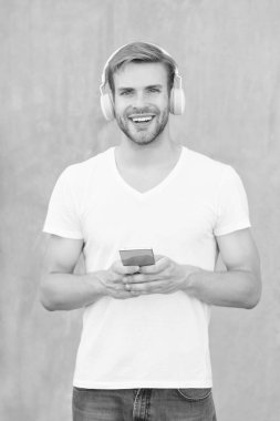 Mutlu adam mp3 müzik listesinin kulaklıkla fotoğrafı. Adam mp3 müzik listesini açıyor. Adam dışarıda mp3 müzik listesi kullanıyor. Beyaz gömlek giyen bir adam mp3 müzik listesini seçer.