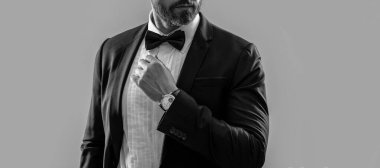 Stüdyodaki resmi smokinli adamın görüntüsü. Resmi smokin giyen bir adamın fotoğrafı. Erkekler resmi smokin giyer. Resmi smokinli adam gri arka planda izole edilmiş..