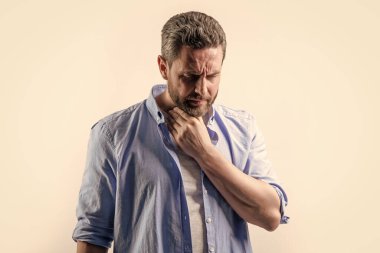 Kirli sakallı, normal gömlekli olgun bir adam. Gri arka planda sakallı, olgun bir adam. Stüdyoda sakallı, olgun bir adam. Sakallı olgun bir adamın fotoğrafı..