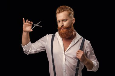 Arka planda yakışıklı berberin fotoğrafı var. Berber adam siyahlar içinde izole edilmiş. Stüdyodaki berber. makaslı berber..