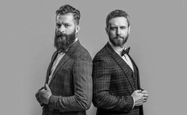 Stüdyoda, resmi kıyafet giyen başarılı adamların fotoğrafı. Resmi takım elbiseli şık erkekler. Smokinli adamlar gri arka planda izole edilmiş. Smokin giymiş iki adam..