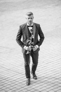 Nişan tarihi. Smokinli adam nişanı kutluyor. Nişan için gül hediyeli bir adam.