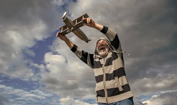 stock image aged senior retired man. mature man at retirement. old man on sky background with toy plane outdoor.