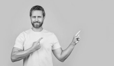 Gülümseyen adamın reklam teklifini gösteren fotoğrafı. Reklam teklifine işaret eden adam sarı üzerine izole edilmiş. Adam arka plandaki reklam teklifini işaret ediyor. Adam reklam teklifini işaret ediyor.