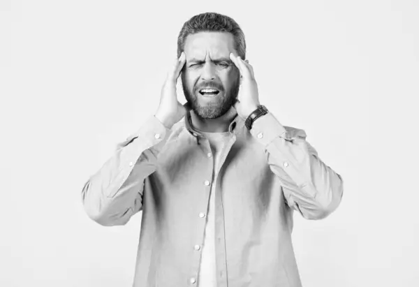 stock image man with headache or migraine isolated on grey background. mature man with headache and migraine in studio. photo of man with migraine headache. man with headache or migraine wear shirt.