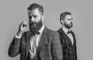 Resmi smokin giymiş zarif beyefendiler, seçici odaklanma. Smokin giyen beyefendi gri arka planda izole edilmiş. Smokinli iki beyefendi. Smokin giyen beyefendilerin stüdyo fotoğrafı..