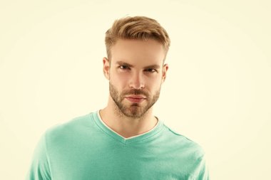 Beyaz, tıraşsız bir adamın stüdyo fotoğrafı. Genç, tıraşsız bir adam yüzü beyaz arka planda izole edilmiş. Tişörtlü traşsız bir adamın yüzü. Traşsız bir adamın portresi..