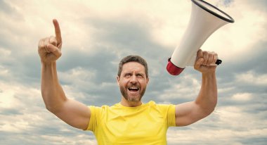 man in yellow shirt shout promo in loudspeaker on sky background.