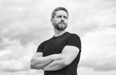 confident man in red shirt crossed hands on sky background.