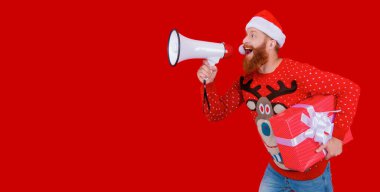 Hoparlörlü ve hediyeli Noel Baba kırmızıda izole edilmiş. Noel hediyesi alışverişi. Yeni yıl tatili duyurusu. Mutlu 2024 yılbaşı. Noel alışverişi. Xmas satış duyurusu. Boşluğu kopyala.