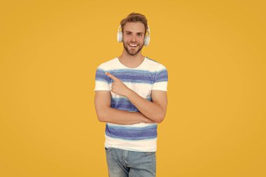 Gülümseyen genç adam çevrimiçi bir derse katılıyor. Kulaklık takan yapılı bir adam. Esmer adam çevrimiçi olarak stüdyoda ders alıyor. Esmer adam sarı arka planda izole edilmiş kulaklık kullanıyor..