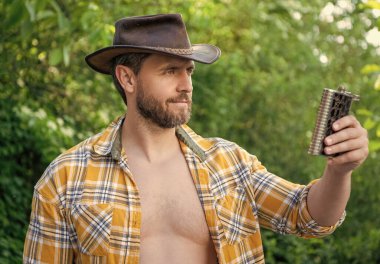 Batılı adam viski şişesi, kareli gömlek ve açık hava gömleği teklif ediyor..