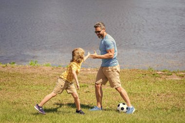 happy childhood of son playing with father. father and son summer activity. son has bonding time with father outdoor. Father and son enjoy a friendly game of football. outdoor experiences. clipart