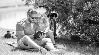 Baba ve çocuk dışarıda kitap okuyor. Baba ve oğul doğada edebi maceralar yaratır. Baba oğul dışarıda okuma zamanı. Baba ve oğul için kutsal bir gelenek. Baba ve oğul kitap okuyor. Aile maceraları.