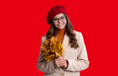 Sonbahar modası. Sarı akçaağaç yapraklarını neşeyle tutan mutlu genç kız. Kırmızıda yaprakları dökülmüş genç bir kız. Sonbahar kızı dökülen yaprakları tutar. Sonbahar ve sonbahar. Sonbahar sezonu. Düşen yapraklar.