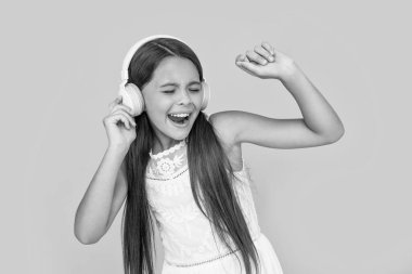 singing teen kid listen music in headphones on yellow background.