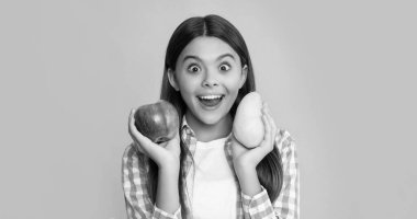 amazed kid with fresh apple and pear on yellow background.