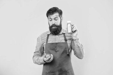 Şaşkınlık içinde önlüklü bir adam limonata şişesine bakıyor sarı arka plan, meyve suyu dükkânı sahibi..