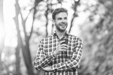 happy young man in checkered shirt with coffee cup.