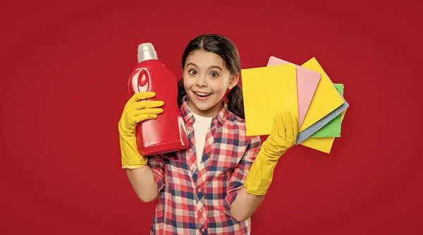 stock image girl holding softener detergent isolated on red. girl with softener detergent in studio. girl with softener detergent on background. photo of girl with softener detergent.