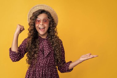 Hasır şapkalı, güneş gözlüklü, uzun esmer kıvırcık saçlı bir çocuk. Boşluğu kopyala.