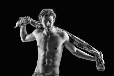 Stüdyoda kaslı vücutlu seksi bir adam var. Gövde üzerinde havlu olan kaslı bir adam. Adamın kaslı gövdesinin fotoğrafı. Gövdesinde havlu olan kaslı adam siyah arka planda izole edilmiş..