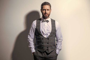 Smokin giyen adam resmi takım elbise giyer. Gri arka planda smokinli bir adam. Smokinli adam stüdyoda. Smokin giyen bir adamın fotoğrafı..