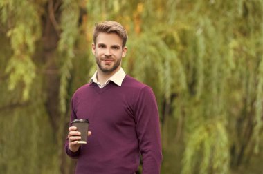 Gülümseyen genç yakışıklı adam sabah kahvesini dışarıda iç..