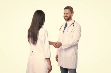 Doktor terapist steteskoplu el sıkışan hemşire. Terapist doktor ve hemşire beyazları izole etmiş. Stüdyoda doktor ve hemşire. Doktorun ve hemşirenin fotoğrafı beyaz önlük giyiyor..