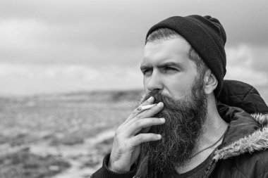 man with beard smoking cigarette, advertisement. bearded man smoking cigarette. photo of man smoking cigarette in the mountain. man smoking cigarette outdoor.