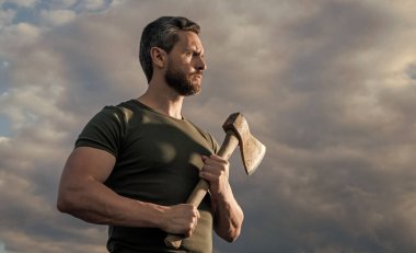 Baltalı güçlü bir adam. Kaslı adam baltayı tutar. Gökyüzündeki vahşi adam.