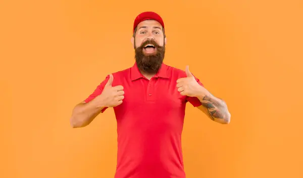 stock image Happy bearded man in casual red cap and tshirt giving double thumbs yellow background, deliveryman.