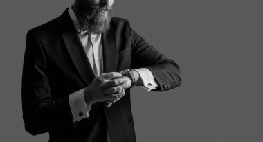 Smokin stüdyosunda çekilen dakik adam. Saati kontrol et, yeri kopyala. Saati ve smokini zamanında kontrol et. Smokinli dakik sakallı adam gri arka planda izole edilmiş saati kontrol et..