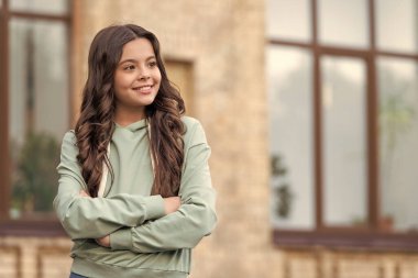 Kendine güveni tam kapüşonlu bir genç kız kollarını açık havada çapraz tutuyor, boşluğu kopyalıyor..