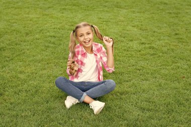 glad teen child sit on green grass outdoor.