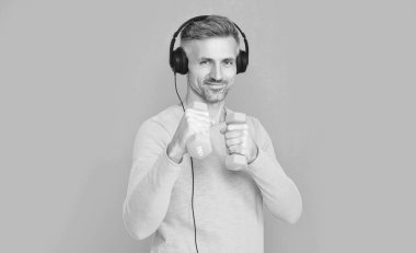 Arka planda müzik kulaklıklı neşeli fitness adamı. Müzik kulaklığı takan fitness oyuncusunun fotoğrafı. Müzik kulaklıklı fitness adamı mavi renkte izole edilmiş. Stüdyoda müzik kulaklıklı fitness adamı..