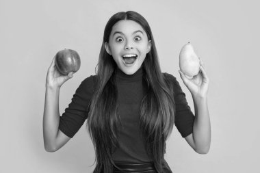 happy amazed child hold fresh apple and pear on yellow background.