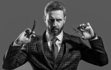 Gri arka planda izole edilmiş berber portresi. Makas ve bıçaklı berber. Stüdyodaki berber. Sakallı berberin fotoğrafı..