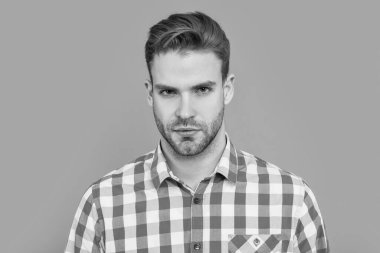 Sıradan bir adamın portresi. Stüdyo fotoğrafı. Sakalı olan beyaz bir adam. Gri arkaplanda kareli gömlekli yakışıklı bir adam izole edilmiş..