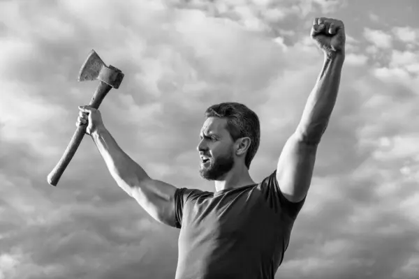 stock image confident man with axe. shouting caucasian man hold ax. brutal man on sky background.