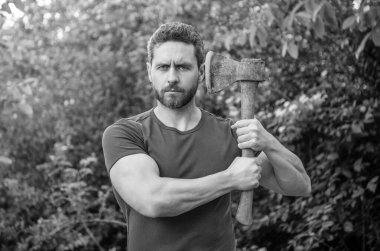 Sakallı, erkeksi bir adamın açık havada keskin bir balta tutarken fotoğrafı..