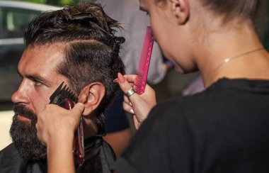 Profesyonel berber ustası olan acımasız adam elektrikli tıraş makinesi kullanıyor. Hipster. Erkek berber bakımı. Kuaför salonundaki sakallı adam. Güzellik ve moda. Saç ve sakal. Taze funky güzellik.