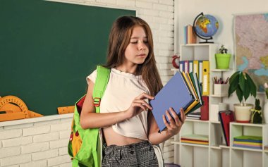 Çalışmaya hazır. Okula dönüyorum. Genç kız tahtaya yakın bir sınıfta çalışıyor. Neşeli çocuk konuyu öğreniyor. Modern eğitim. Bilgi günü. Çocuk öğrenci kitap tutuyor. Kız üniversite öğrencisi..